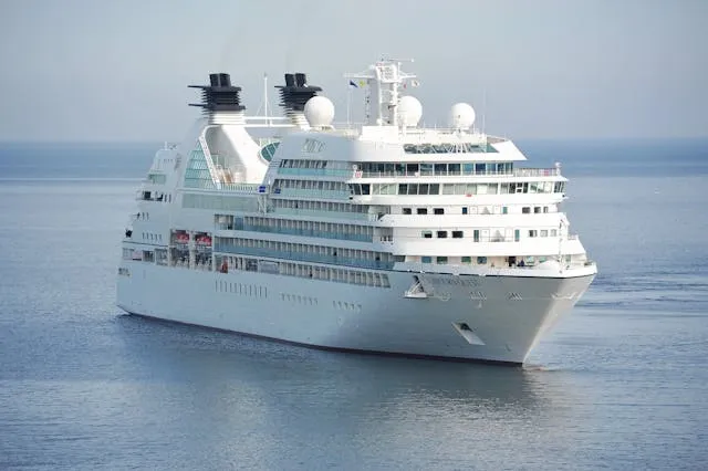 A white cruise ship sails through the open ocean under a clear sky, symbolizing luxury cruise travel from Galveston.